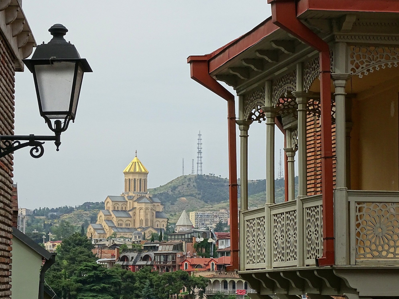 Carved wooden balconies in the old town of Tbilisi, Georgia, with the Holy Trinity Cathedral on the hill behind